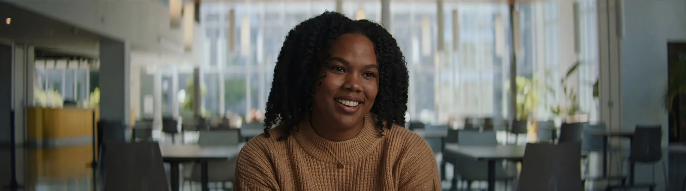 A woman smiling during an interview in a bright atrium